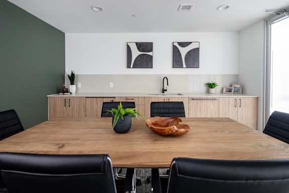 A conference room with a wooden table, chairs, and two framed pictures on the wall.