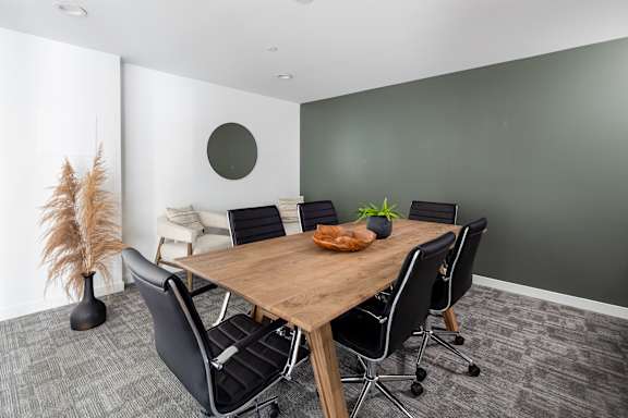 A conference room with a wooden table and black chairs.