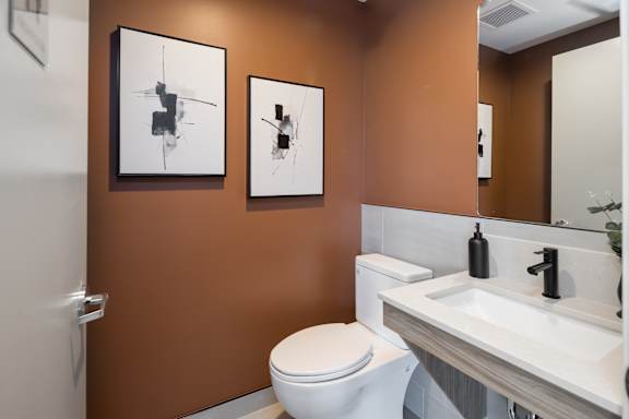 A bathroom with brown walls and a white toilet and sink.