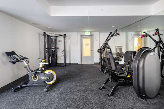 A gym with a variety of equipment including a stationary bike and a rowing machine.