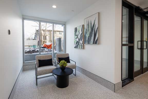 A modern living room with a glass door and a painting on the wall.