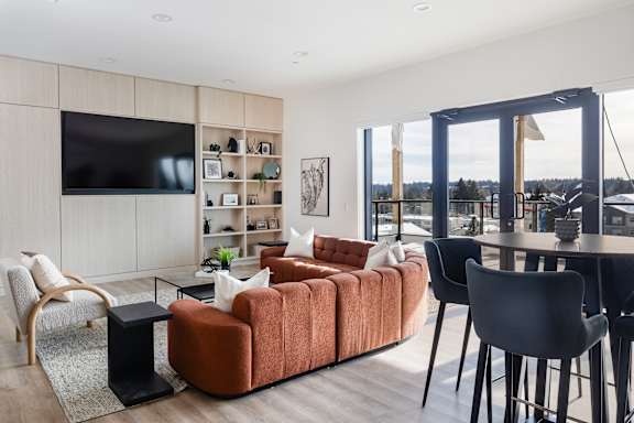 A modern living room with a large orange sofa and a flat screen TV mounted on the wall.