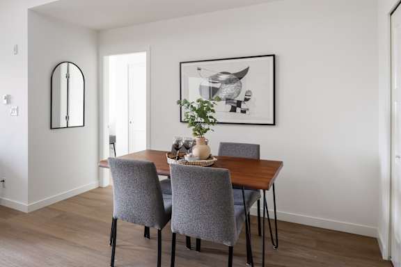 A dining room with a wooden table and grey chairs.
