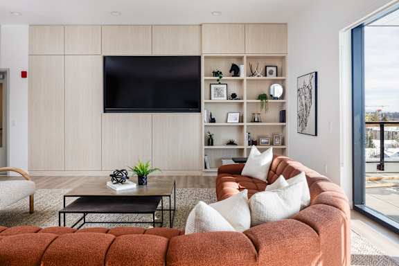 A modern living room with a brown couch and a flat screen TV mounted on the wall.