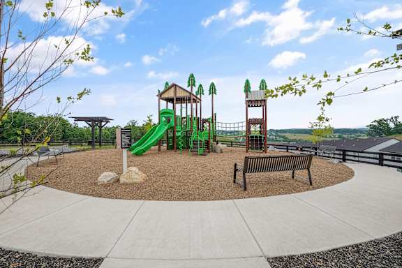 A playground with a green slide and a brown bench.