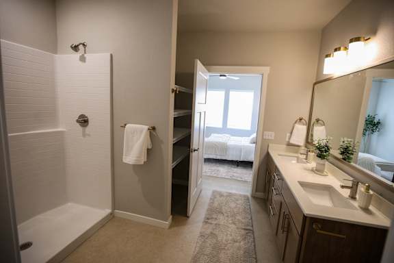 A bathroom with a white tiled shower and a white sink.