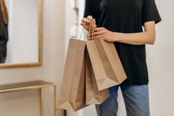 A person holding two brown paper bags.