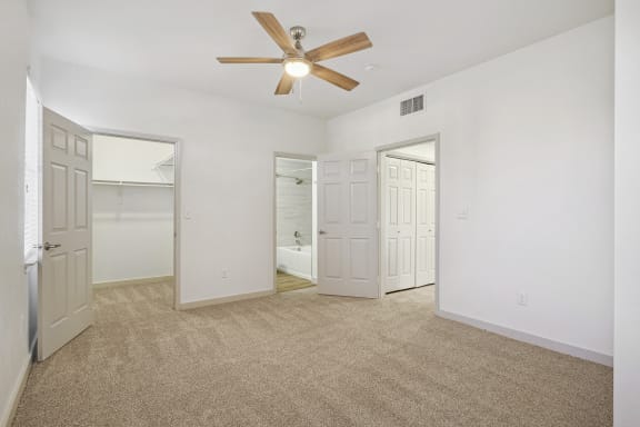 the living room of an empty apartment with white walls and a ceiling fan at The Legends at Eagle Mountain Lake, Texas