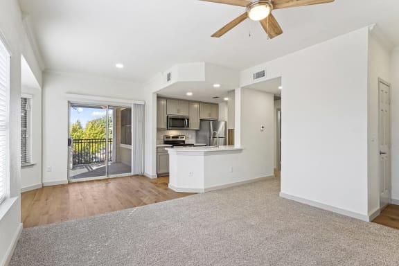 an empty living room with a kitchen and a ceiling fan at The Legends at Eagle Mountain Lake, Texas, 76179