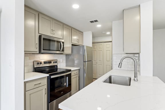 a white kitchen with stainless steel appliances and white counter tops at The Legends at Eagle Mountain Lake, Texas