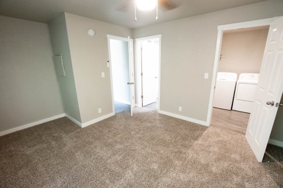 an empty room with carpeting and a door to a laundry room