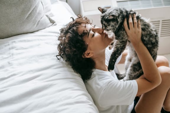 a woman laying in bed with a cat on her face