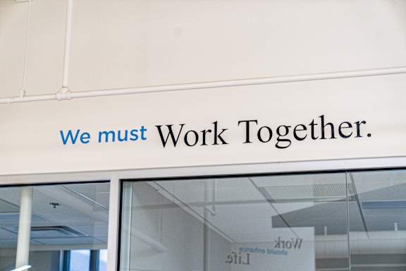 A sign on a building that says "We must work together.".