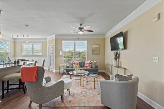 a living room with a ceiling fan and a flat screen tv at The Residences at Bluhawk Apartment Homes, Overland Park
