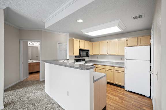 A kitchen with white appliances and wooden cabinets.at The Claremont Apartment Homes, Kansas