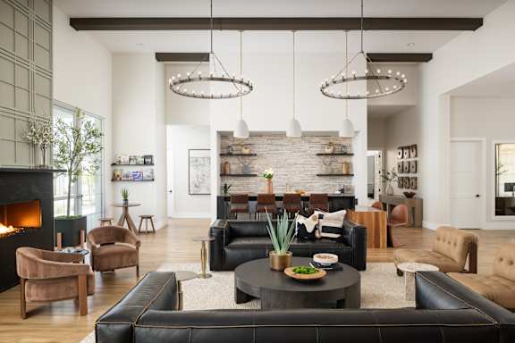 A modern living room with a black leather couch and a fireplace.