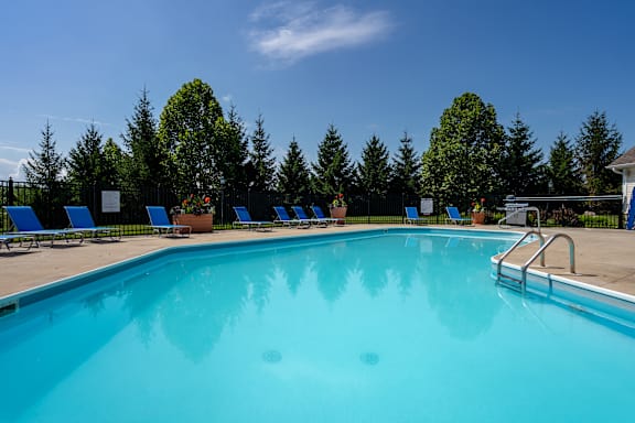A large swimming pool surrounded by lounge chairs and umbrellas.