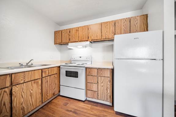 A kitchen with wooden cabinets and white appliances.
