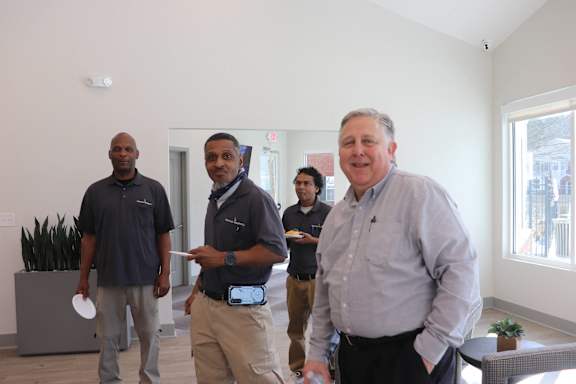 A man in a grey shirt is standing in a room with three other men.