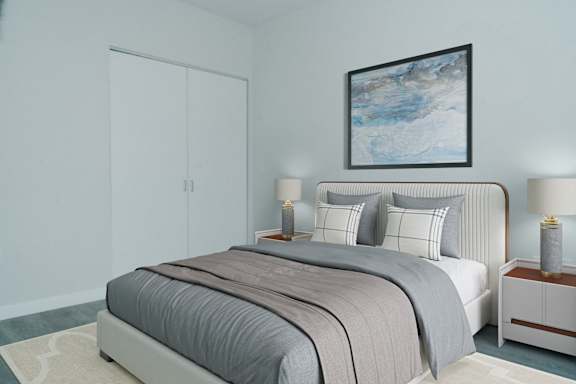 A bed with a grey comforter and pillows is in the image.