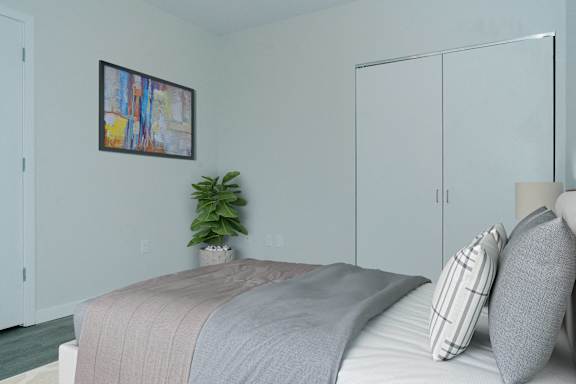 A bedroom with a bed, pillows, a plant, and a painting on the wall.
