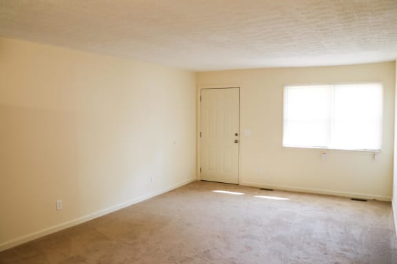 an empty living room with a door and a window