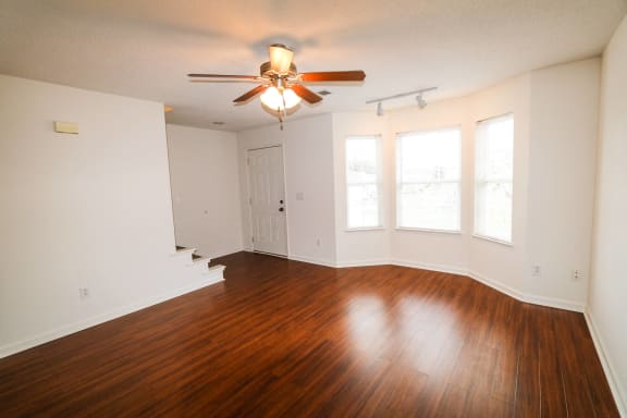an empty living room with wood floors and a ceiling fan