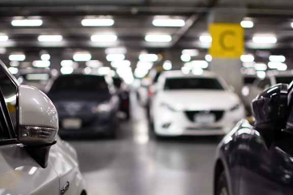 A parking garage with cars parked in rows and a yellow sign with a "C" on it.