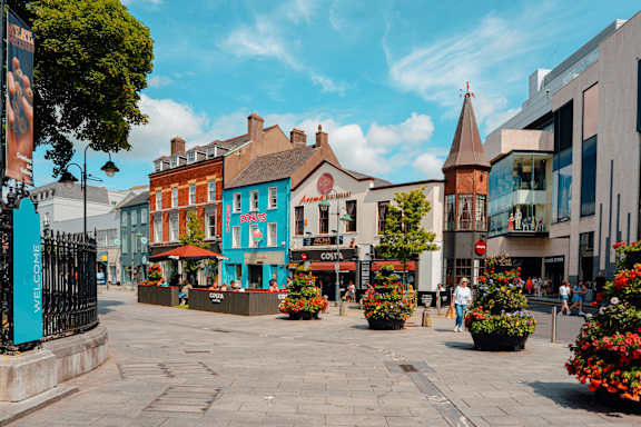 A street view of a town with buildings and people walking.
