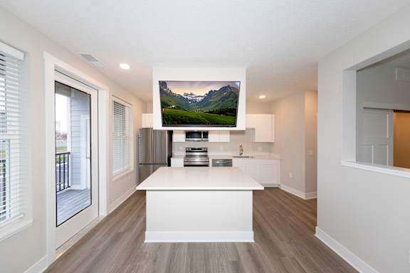 A modern kitchen with a large island and a mountain displayed on the wall.