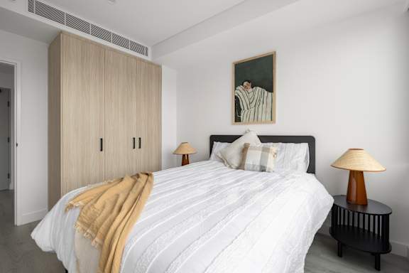 A bedroom with a bed, a lamp, and a painting on the wall.