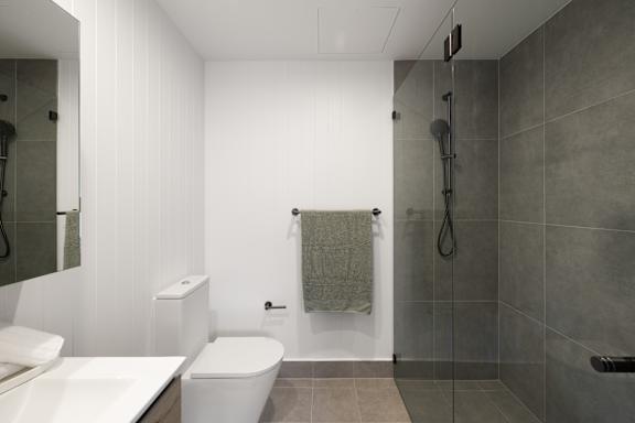 A bathroom with a white toilet, sink, and shower.
