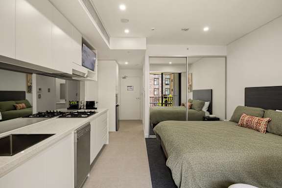 A modern bedroom with a large bed and a kitchen area with a stove.