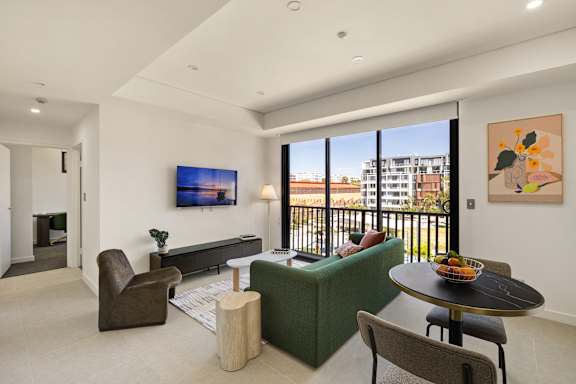 A living room with a green couch, a brown chair, a coffee table, and a painting on the wall.