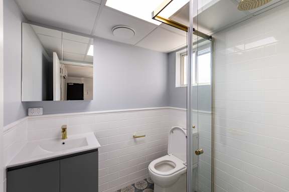 A white bathroom with a toilet, sink, and mirror.