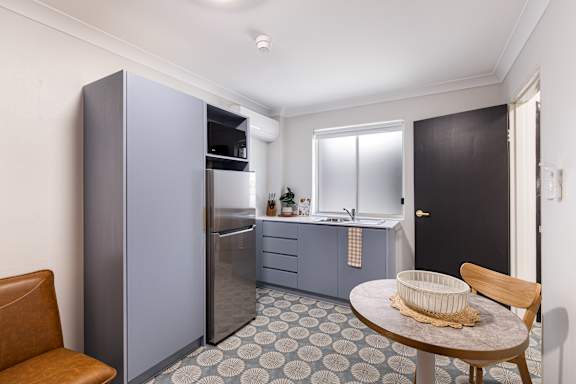 A kitchen with a refrigerator, sink, and a table with a basket on it.