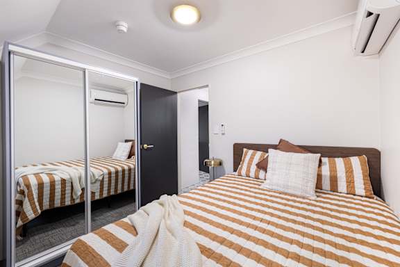 A bedroom with a bed, a mirror, and a door.