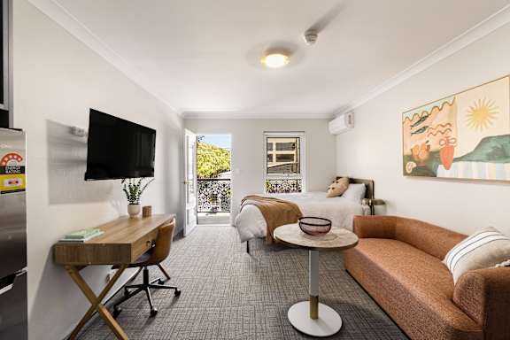 A living room with a couch, a chair, a desk, and a television.