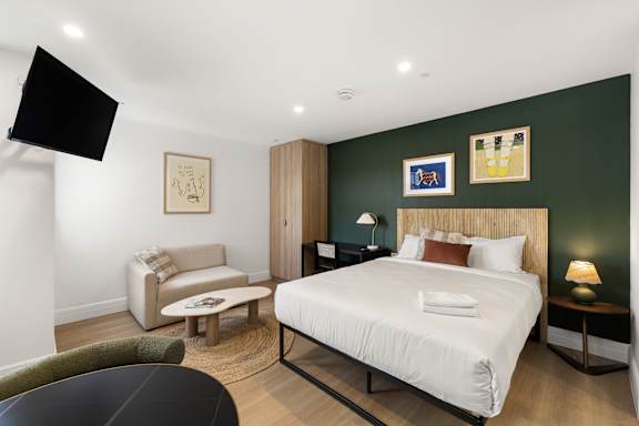 A bedroom with a large bed, a chair, and a painting on the wall.