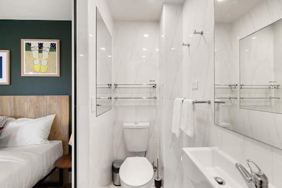 A white bathroom with a toilet, sink, and mirror.