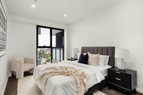 A bedroom with a large bed and a chair.