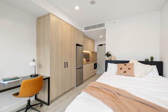 A bedroom with a bed, desk, and chair.