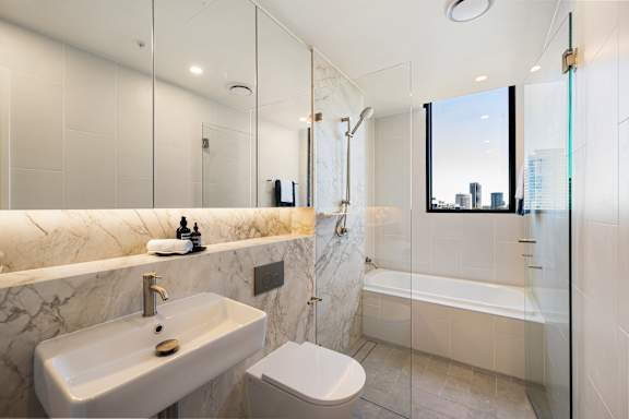 A modern bathroom with a marble sink and a large mirror.