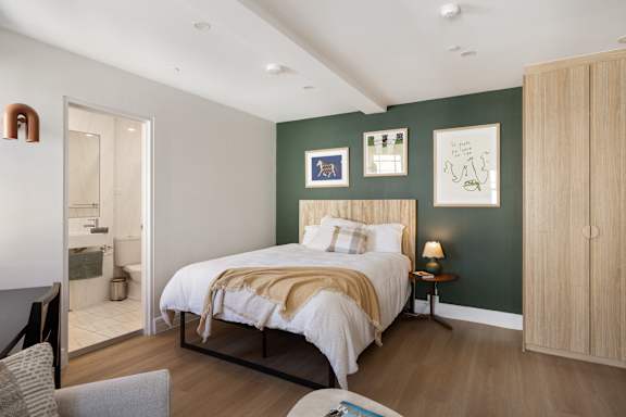 A bedroom with a bed, a chair, and a cabinet.