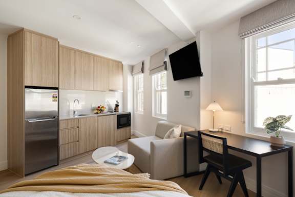A modern kitchen with a refrigerator, sink, and a dining table with chairs.
