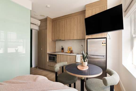 A kitchen with a table and chairs in the foreground and a refrigerator in the background.