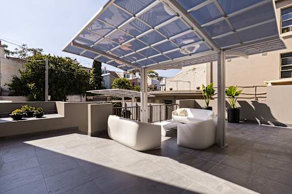 A patio with white furniture and a glass roof.