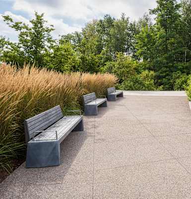 A concrete walkway with benches and a metal railing.