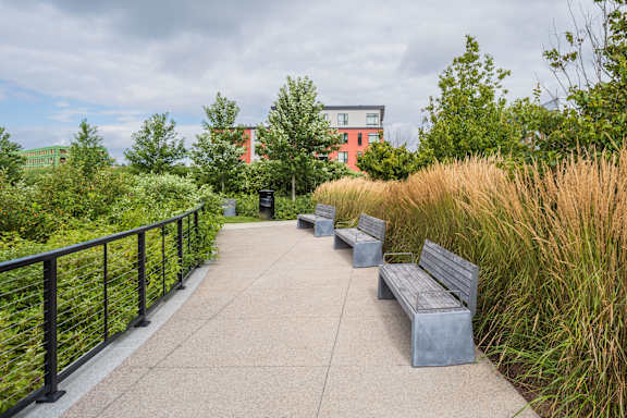 A concrete walkway with benches and a metal railing.