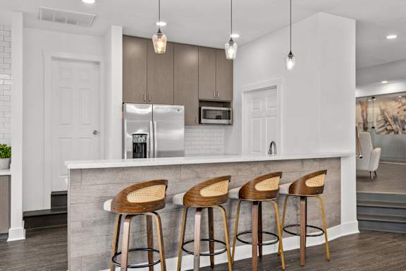A kitchen with a white counter and bar stools.